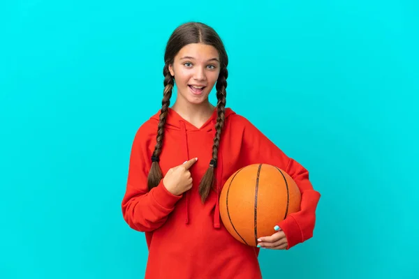 在蓝色背景下打篮球的一个高加索小女孩 脸上带着惊讶的表情 — 图库照片