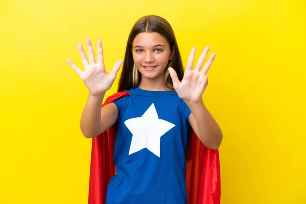 小さいですCaucasianスーパーヒーロー女の子絶縁オンイエローバックカウント9とともに指 — ストック写真