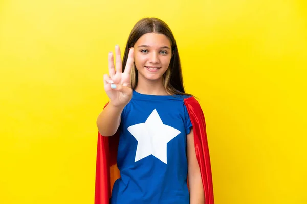 小さなCaucasianスーパーヒーロー女の子孤立しました上の黄色の背景幸せとカウント3とともに指 — ストック写真