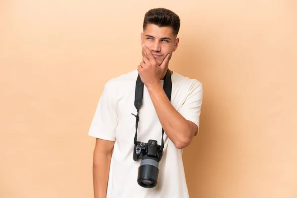 Νεαρός Φωτογράφος Καυκάσιος Άνδρας Απομονωμένος Μπεζ Φόντο Έχοντας Αμφιβολίες Και — Φωτογραφία Αρχείου