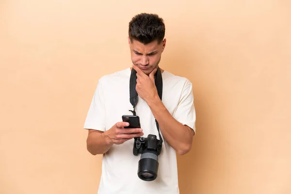 Junger Fotograf Kaukasischer Mann Isoliert Auf Beigem Hintergrund Denkt Und — Stockfoto