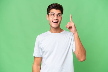 Young caucasian handsome man over isolated background intending to realizes the solution while lifting a finger up