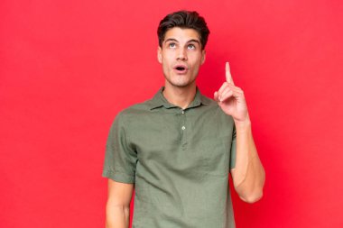 Genç, beyaz, yakışıklı bir adam kırmızı arka planda izole edilmiş.