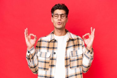 Zen pozisyonunda kırmızı arka planda izole edilmiş beyaz yakışıklı bir adam.