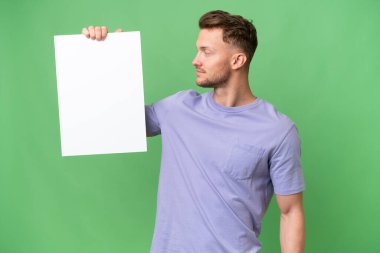 Sarışın, beyaz, soyutlanmış bir geçmişi olan, elinde boş bir levha olan genç bir adam.