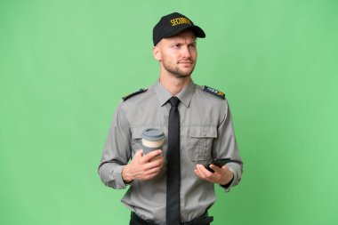 Kafkasyalı genç bir adam izole edilmiş arka planda kahve ve bir şeyler düşünürken cep telefonu tutuyor.