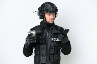 SWAT elemanı izole edilmiş beyaz arka planda elinde kahve ve bir cep telefonu tutuyor.