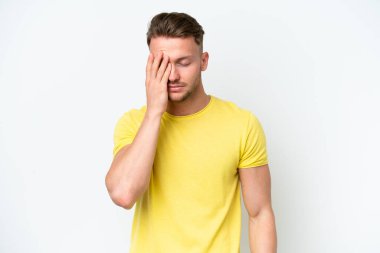 Beyaz arka planda başı ağrıyan genç, sarışın, beyaz bir adam.