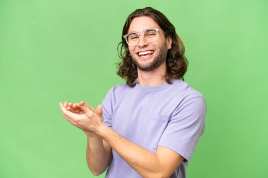 Genç yakışıklı adam, izole edilmiş arka planda alkışlıyor.