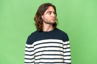 Tecrit edilmiş genç ve yakışıklı bir adam yan tarafa bakıyor.