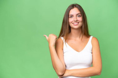 Tecrit edilmiş arka planda genç ve güzel bir kadın bir ürün sunmak için kenarı işaret ediyor.