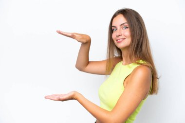 Beyaz arka planda izole edilmiş genç beyaz bir kadın ilan vermek için kopyalama alanı tutuyor.