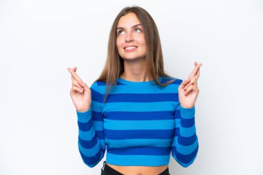 Beyaz arka planda izole edilmiş beyaz tenli genç bir kadın parmaklarını çapraz yapıp en iyisini diliyor.