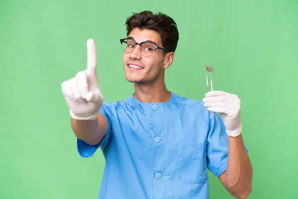 Jovem Dentista Homem Segurando Ferramentas Sobre Fundo Isolado Mostrando Levantando — Fotografia de Stock