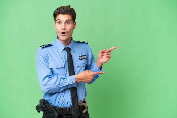 Jonge Politieman Geïsoleerde Achtergrond Verrast Wijzend Kant — Stockfoto