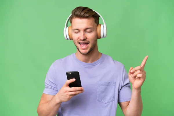 Jonge Blonde Kaukasische Man Geïsoleerde Achtergrond Luisteren Muziek Met Een — Stockfoto