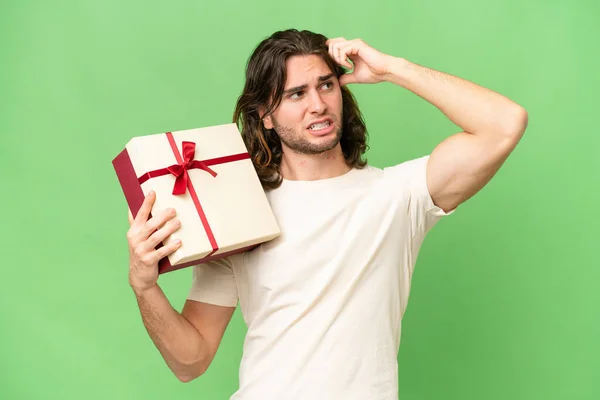 Young Handsome Man Holding Gift Isolated Background Having Doubts Confuse — Stock Photo, Image