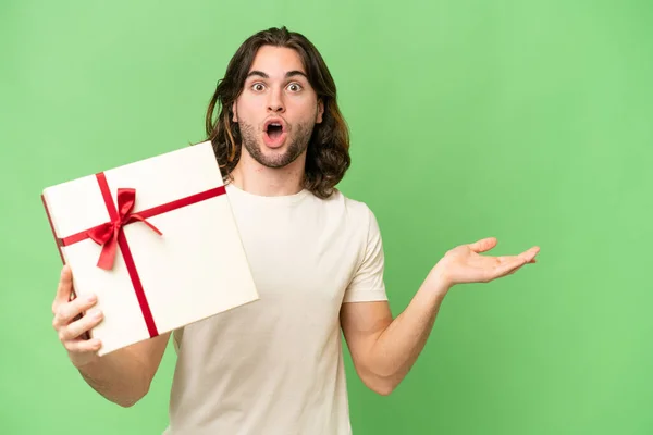 Young Handsome Man Holding Gift Isolated Background Surprised Pointing Side — Stock Photo, Image