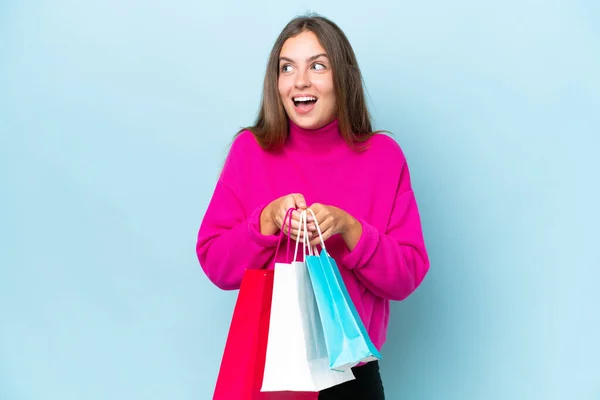 Jonge Mooie Vrouw Geïsoleerd Blauwe Achtergrond Met Winkeltassen Verrast — Stockfoto