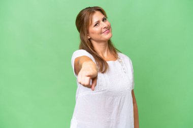 Orta yaşlı beyaz kadın izole edilmiş arka planda mutlu bir ifadeyle öne bakıyor.