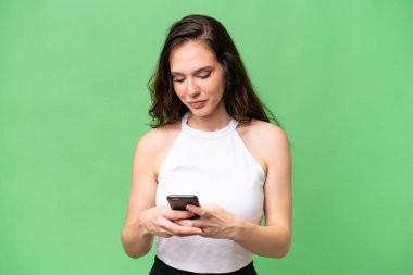 Kafkasyalı genç bir kadın izole edilmiş arka planda cep telefonuyla mesaj gönderiyor.