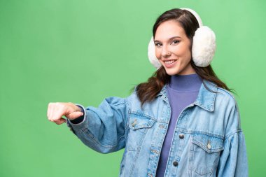 İzole edilmiş arka planda kışlık kuklalar takan beyaz bir kadın baş parmak işareti yapıyor.