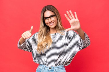 Genç Uruguaylı kadın kırmızı arka planda izole edilmiş. Parmakları olan altı kişi saydım.