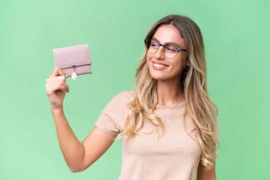 Genç Uruguaylı kadın cüzdanını mutlu bir ifadeyle izole edilmiş arka planda tutuyor.
