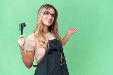 Genç Uruguaylı kuaför kadın izole arka planda. Davet etmek için ellerini yana uzatıyor.