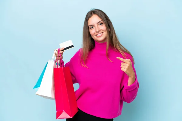 Jonge Mooie Vrouw Geïsoleerd Blauwe Achtergrond Met Boodschappentassen Een Creditcard — Stockfoto