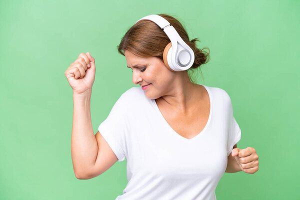 Middle-aged caucasian woman over isolated background listening music and dancing