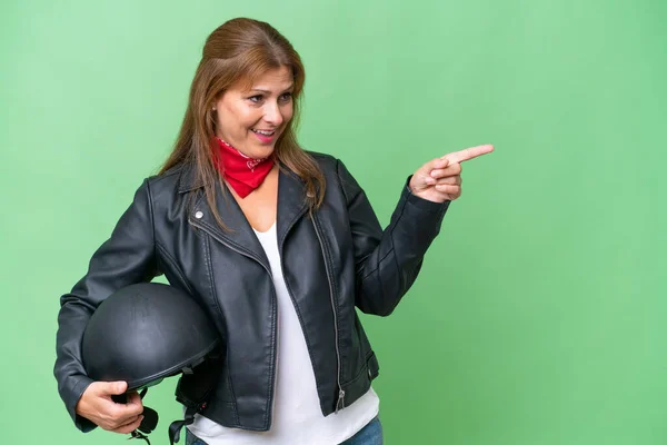 中年Caucasian女性とともにオートバイヘルメット上の隔離された背景指差し指側と製品を提示 — ストック写真