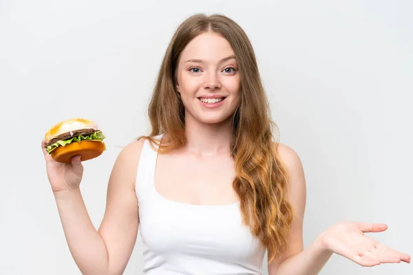 Młoda Ładna Kobieta Trzyma Hamburgera Odizolowany Białym Tle Wstrząśniętym Wyrazem — Zdjęcie stockowe