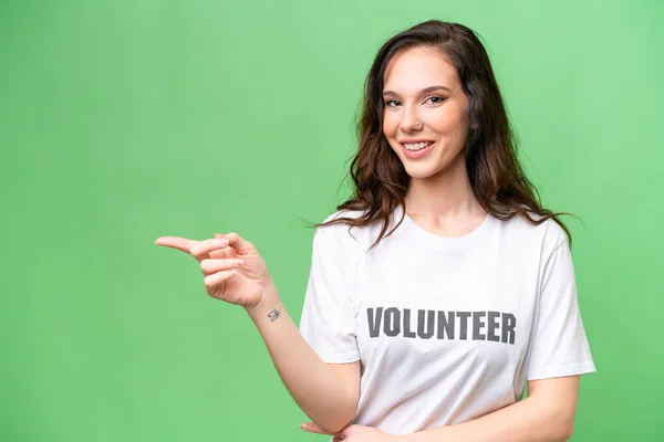 stock image Young volunteer caucasian woman over isolated background pointing finger to the side