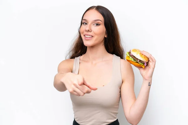 Młoda Kaukaska Kobieta Trzyma Hamburgera Białym Tle Wskazuje Palcem Ciebie — Zdjęcie stockowe