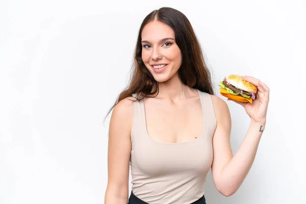 Młoda Kaukaska Kobieta Trzyma Hamburgera Izolowane Białym Tle Uśmiechając Się — Zdjęcie stockowe