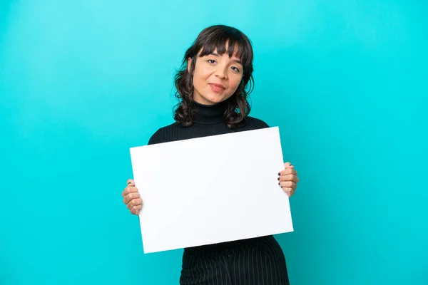 一个年轻的拉丁女人 被蓝色的背景隔离着 手里拿着一张空空的标语牌 脸上带着快乐的表情 — 图库照片
