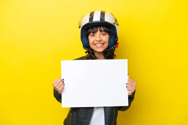 stock image Young latin woman with a motorcycle helmet isolated on yellow background holding an empty placard with happy expression