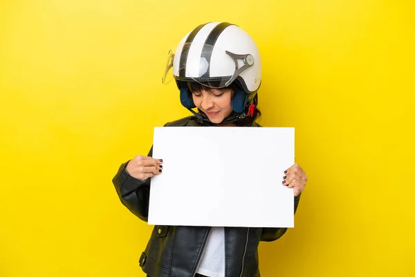 stock image Young latin woman with a motorcycle helmet isolated on yellow background holding an empty placard with happy expression