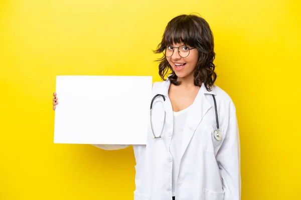 年轻的医生拉汀女士 被隔离在黄色背景下 手里拿着一张空空的标语牌 脸上带着快乐的表情 — 图库照片