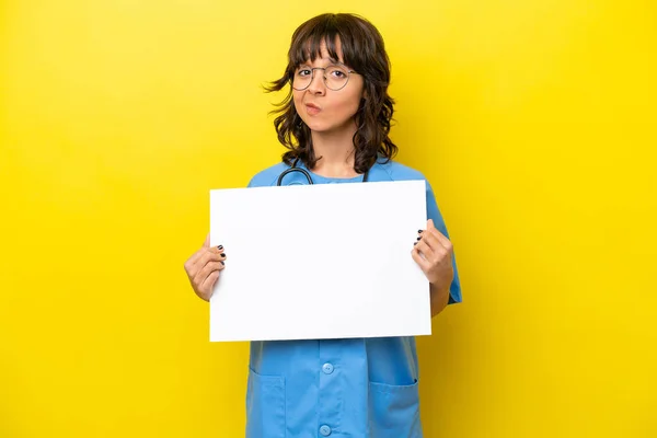 stock image Young nurse doctor woman isolated on yellow background holding an empty placard