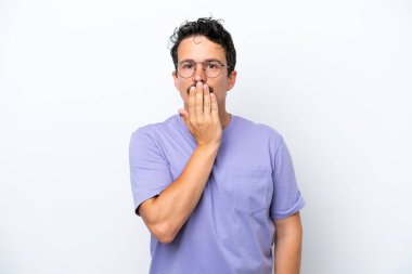 Bıyıklı genç adam beyaz arka planda, ağzı eliyle kapatıyor.