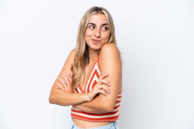 Beyaz arka planda izole edilmiş genç beyaz kadın, omuzlarını kaldırırken şüphe jestleri yapıyor.