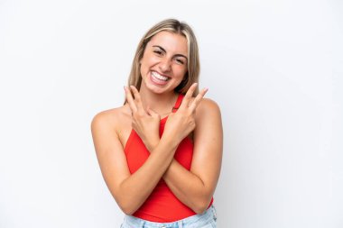 Beyaz arka planda izole edilmiş genç beyaz kadın gülümsüyor ve zafer işareti gösteriyor.