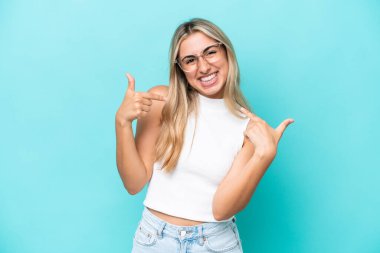 Mavi arka planda soyutlanmış, gururlu ve kendini beğenmiş beyaz bir kadın.