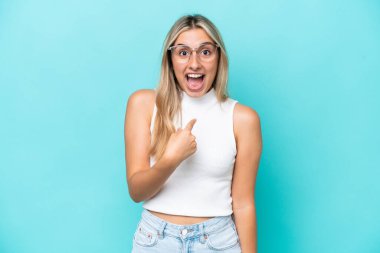 Mavi arka planda yalıtılmış beyaz bir kadın. Şaşırtıcı bir yüz ifadesi var.