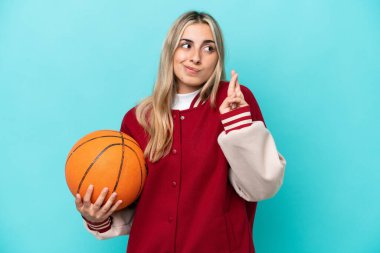 Beyaz tenli genç basketbolcu kadın mavi arka planda izole edilmiş ve şans diliyor.