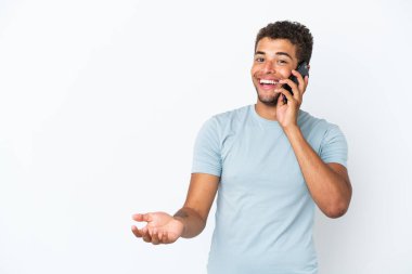 Beyaz arka planda izole edilmiş yakışıklı Brezilyalı bir adam cep telefonuyla sohbet ediyor.