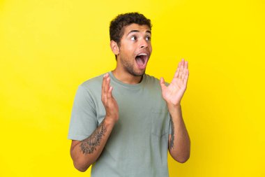 Sarı arka planda yalıtılmış yakışıklı Brezilyalı bir adam. Şaşırtıcı bir yüz ifadesi var.