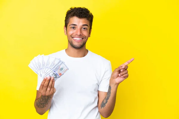 Νεαρός Βραζιλιάνος Που Παίρνει Πολλά Χρήματα Απομονωμένος Κίτρινο Φόντο Δείχνοντας — Φωτογραφία Αρχείου